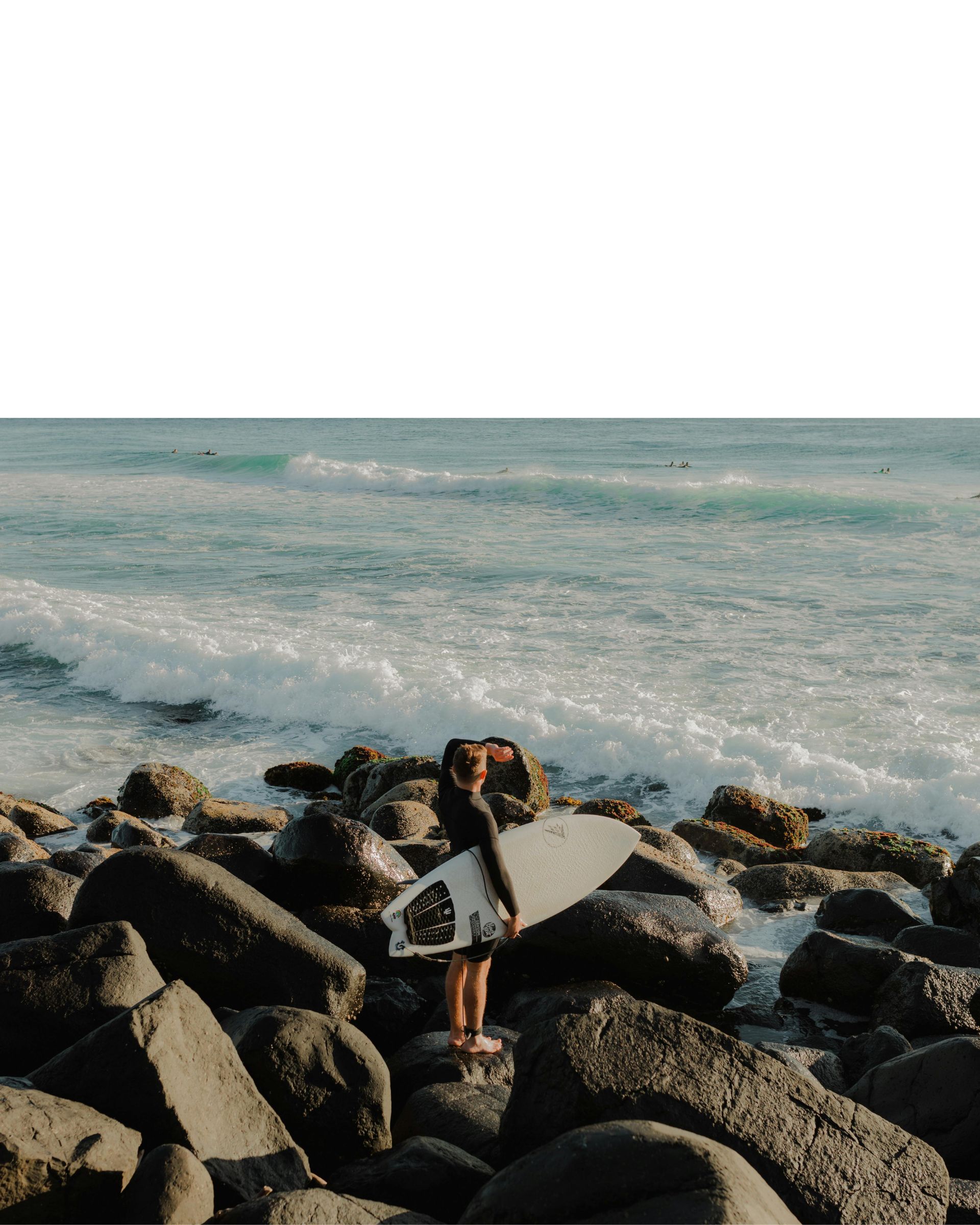 A surfer with a board looking out at the waves in Burleigh Heads